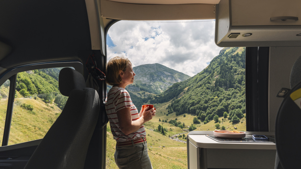 Een volwassen vrouw geniet vanuit haar camper van het uitzicht op de vallei in de Franse Pyreneeën