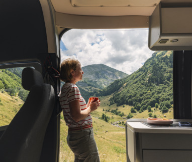 Een volwassen vrouw geniet vanuit haar camper van het uitzicht op de vallei in de Franse Pyreneeën