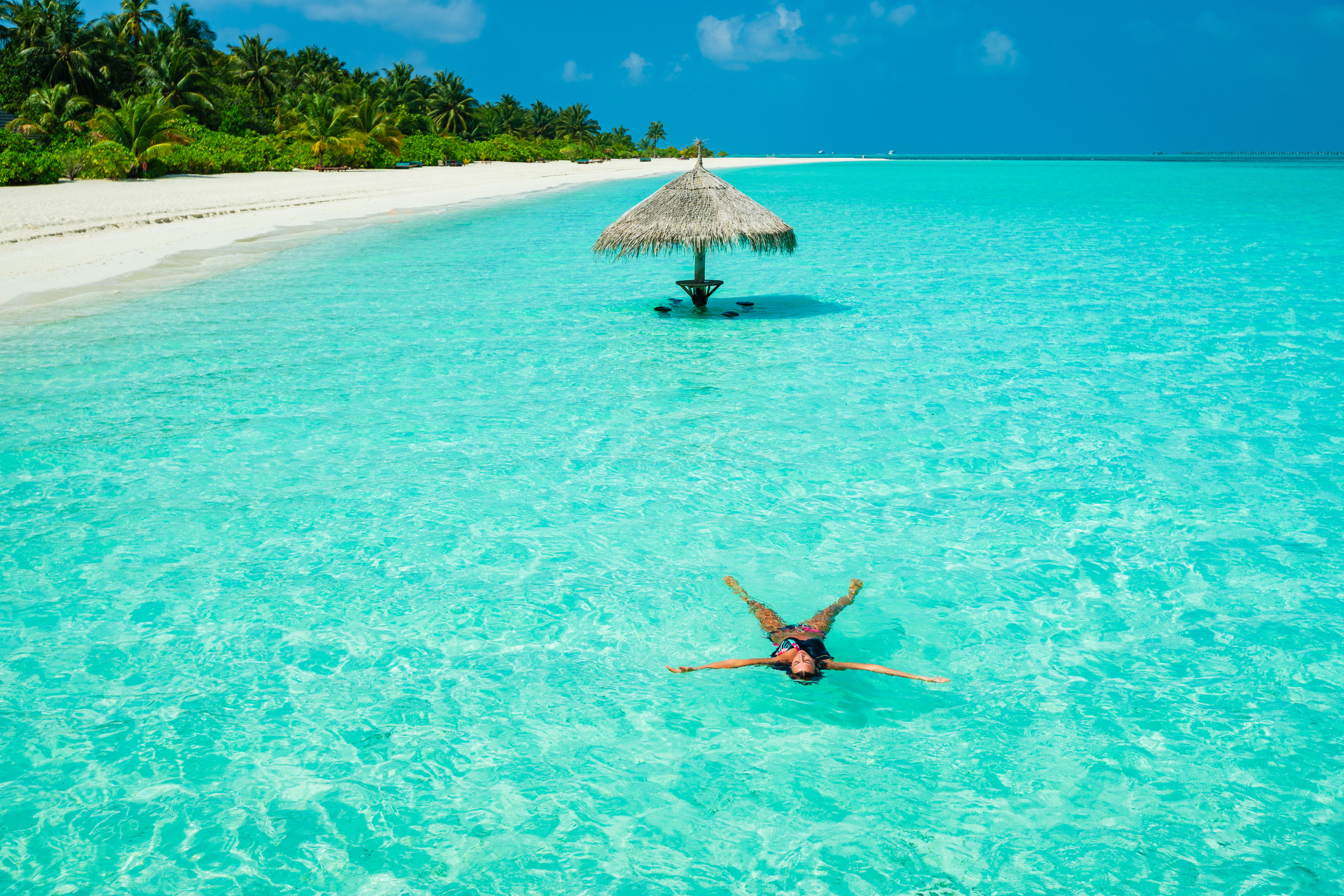 Een jonge, mooie vrouw geniet van een duik op het vakantie-eiland Dhiffushi in het Zuid-Ari-atol, op de Malediven.
