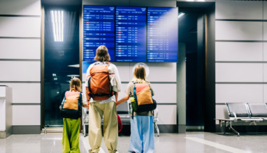Een gezin bekijkt de vluchten op het vertrekbord op de luchthaven