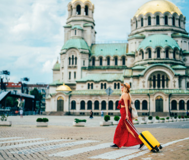 Een individuele reiziger loopt met een gele koffer over het plein voor de Alexander Nevski-kathedraal in Sofia, Bulgarije. Een jonge toerist verkent de stad, geniet van culturele bezienswaardigheden en ontdekt iconische Europese monumenten tijdens een zomervakantie.