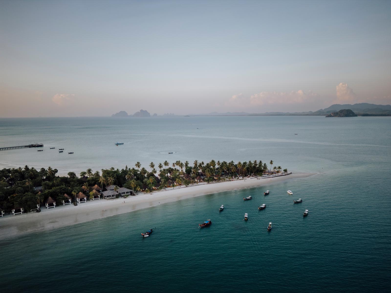 Drone-opname van een tropisch eiland met palmbomen, een wit zandstrand en langstaartboten in zee bij Koh Muk in Thailand