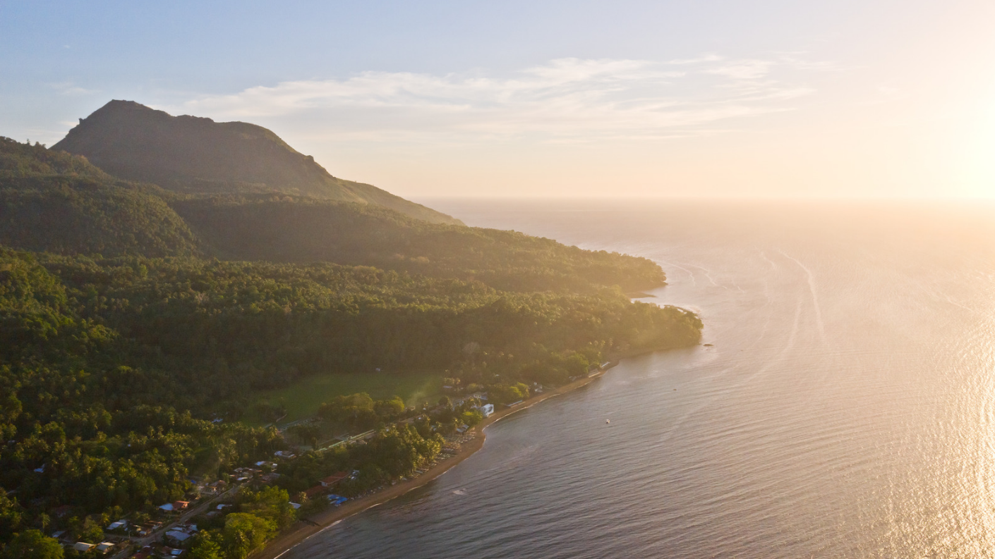 Luchtfoto van de groene hellingen van vulkaan Mount Hibok-Hibok en de kustlijn bij zonsondergang op het eiland Camiguin in de Filipijnen.