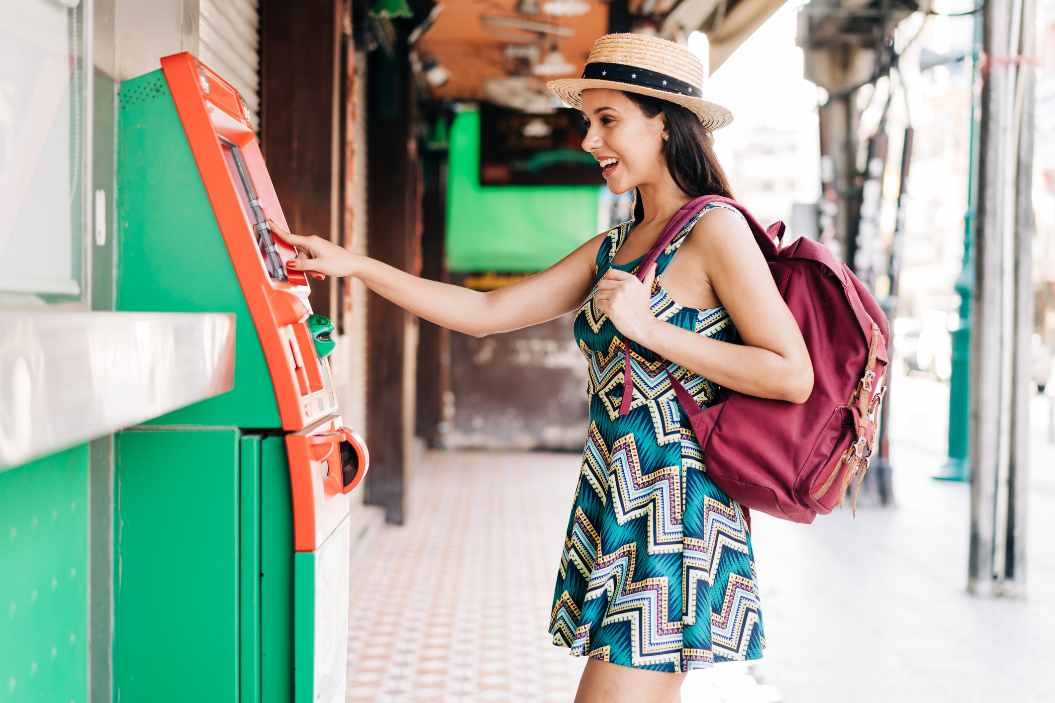 Een jonge, brunette reizigster die geld opneemt uit een geldautomaat in Thailand, Azië. Een Spaanse backpackster van in de twintig in een zomerjurk die zich bezighoudt met haar financiële zaken.