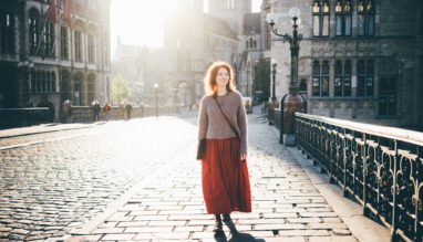 Meisje dat bij zonsopgang door het stadscentrum loopt en in haar eentje van de bezienswaardigheden geniet. Vrouw in tegenlicht. Gent, België