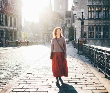Meisje dat bij zonsopgang door het stadscentrum loopt en in haar eentje van de bezienswaardigheden geniet. Vrouw in tegenlicht. Gent, België