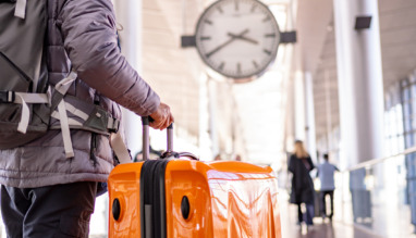 toerist die naar het vertrek- en aankomstbord op de internationale luchthaven kijkt