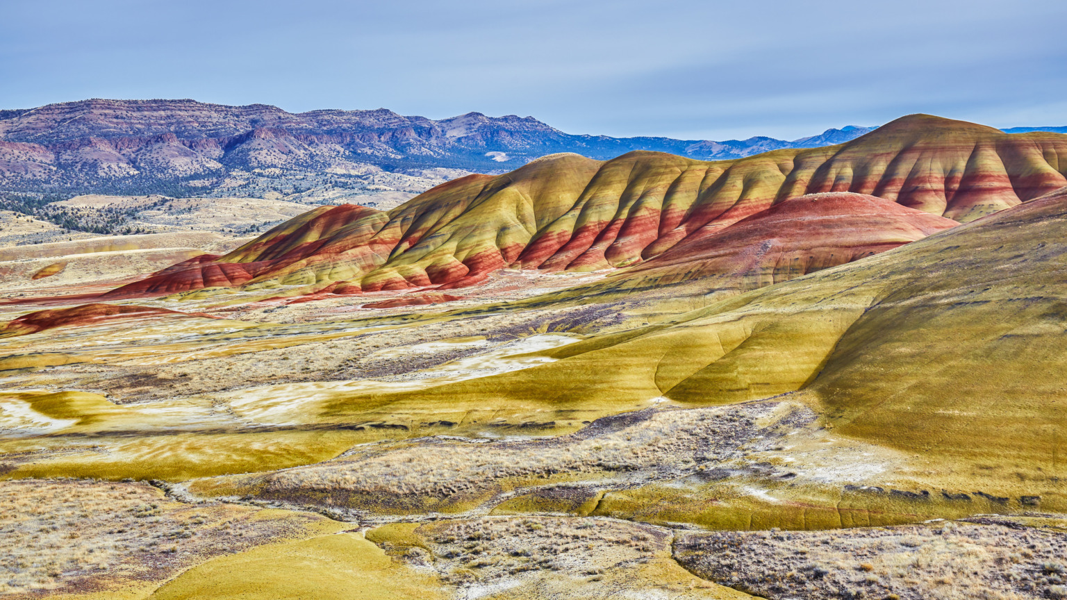 Als onderdeel van het John Day Fossil Beds National Monument vormen de Painted Hills een geografisch geschiedenisboek. De gekleurde lagen vertellen het verhaal van veranderende klimaten over tientallen miljoenen jaren: de dieprode banden ontstonden in warme, vochtige periodes, terwijl de gele en zwarte lagen wijzen op drogere tijdperken.