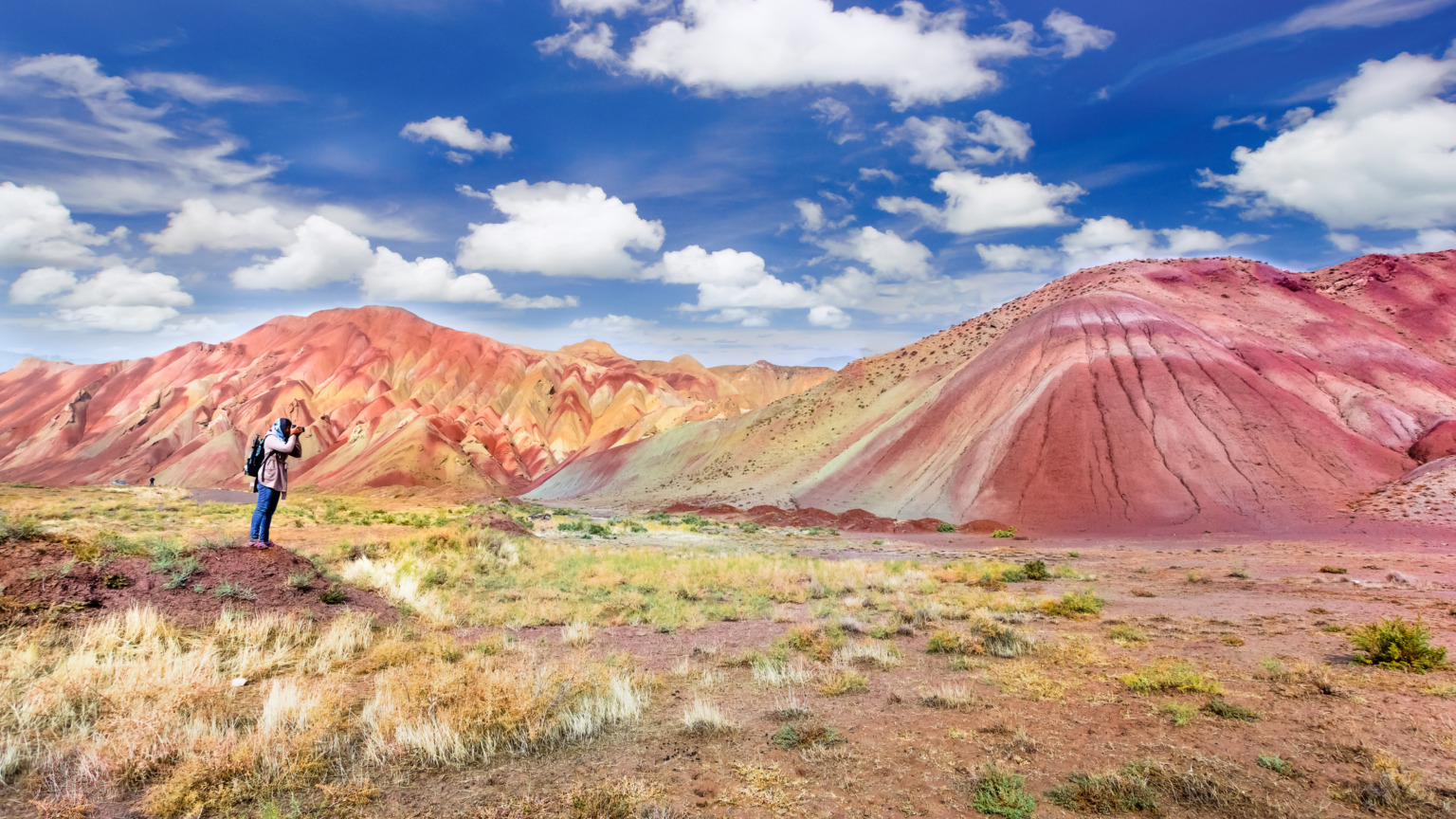 In het noordwesten van Iran liggen de Aladaghlar Rainbow Mountains, een van 's werelds meest uitgestrekte en surrealistische regenbooglandschappen. De golvende heuvelketens in koperrood, felgeel en groen zijn een droom voor elke reiziger. Echter, door de gespannen geopolitieke situatie en de veiligheidsrisico's in het land is deze regio momenteel helaas niet verantwoord te bezoeken. Het herinnert ons eraan dat de toegankelijkheid van 's werelds mooiste natuurwonderen soms snel kan veranderen.