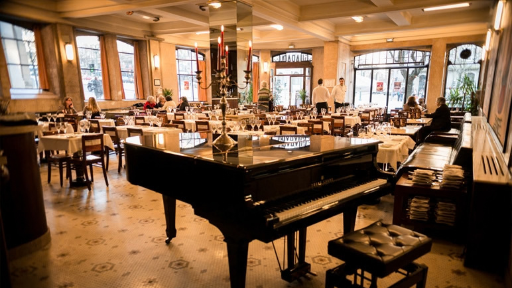Zwarte vleugelpiano met kandelaar in het sfeervolle, klassieke interieur van Café Guarany in Porto
