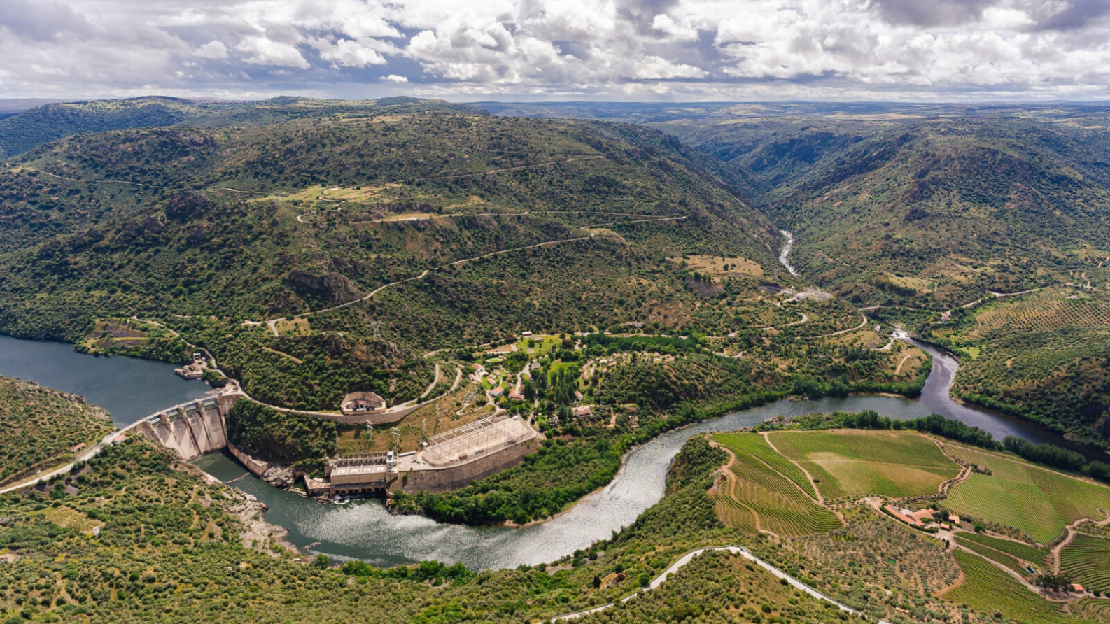 Luchtfoto van een stuwdam en waterkrachtcentrale in de meanderende Douro-rivier omgeven door groene heuvels