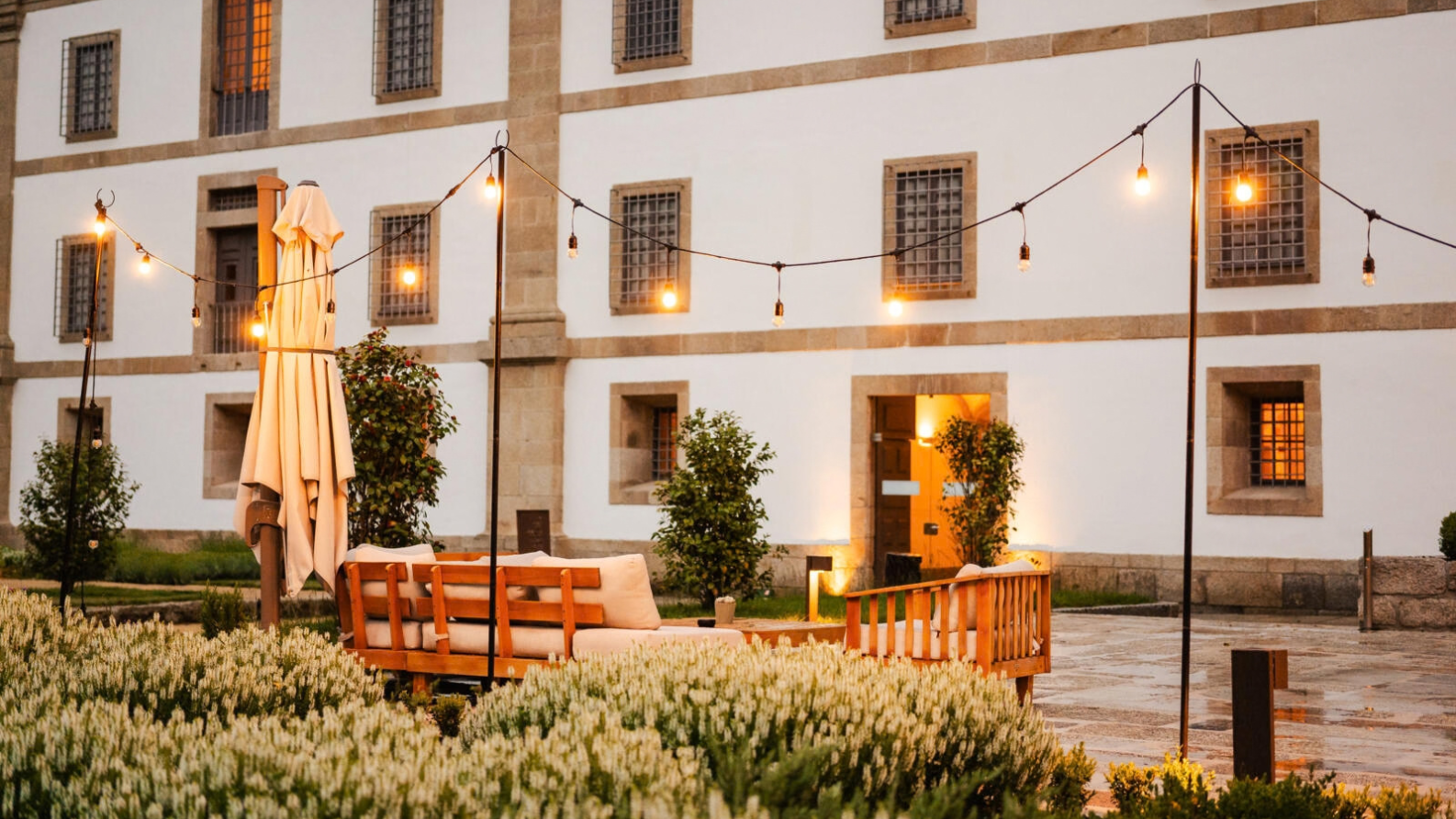 Verlicht terras met lichtslingers, houten zitbanken en lavendel bij de historische gevel van Hotel MS Collection