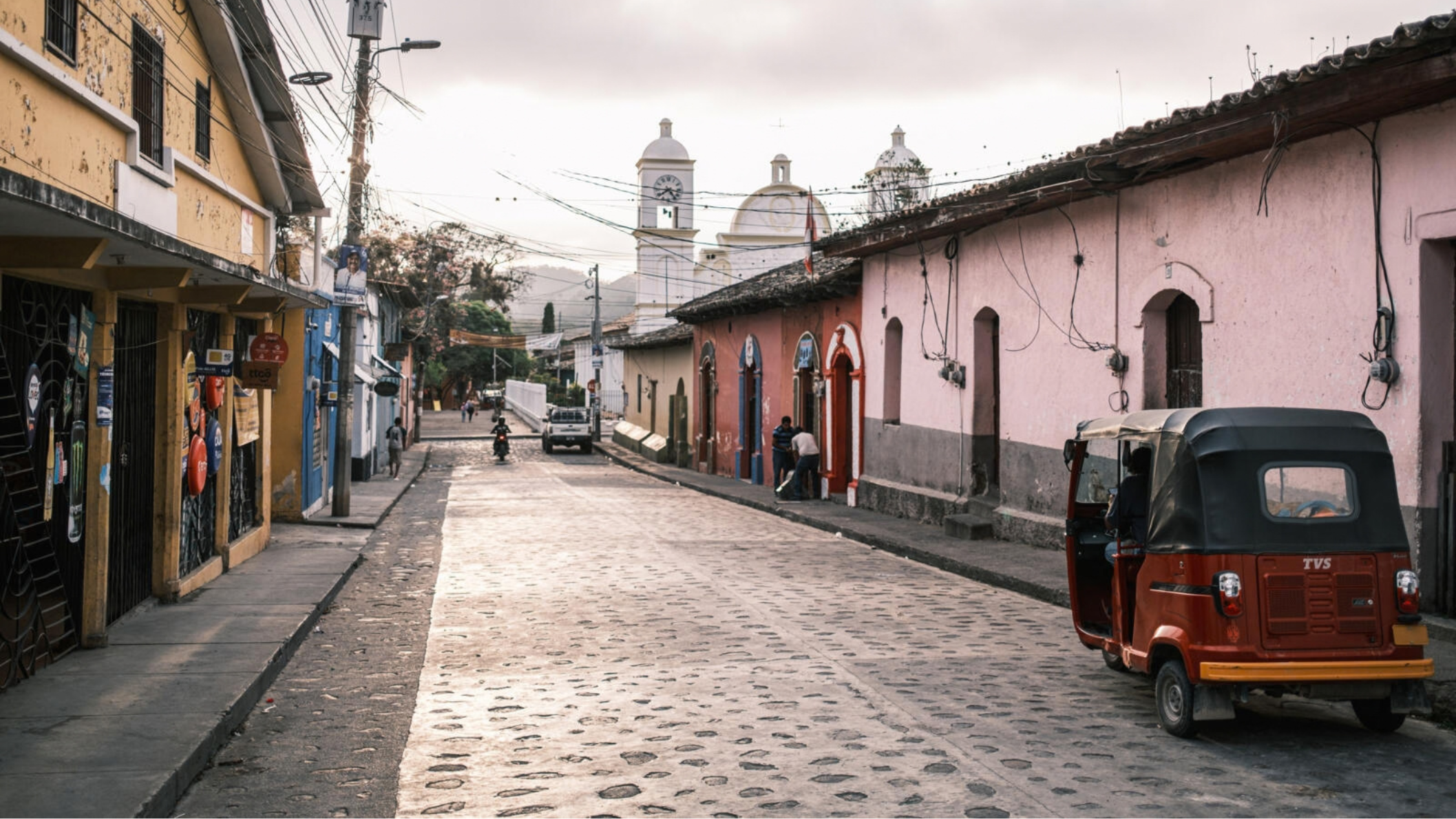 Koloniale straat in Gracias, Honduras, met kleurrijke huizen, een kerk en een rode tuk-tuk