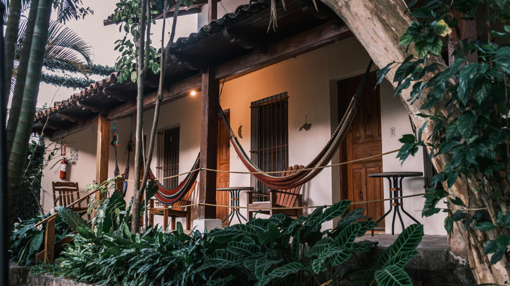 Veranda van Hotel Posada Las Guancascos met hangmatten, houten meubels en tropische planten