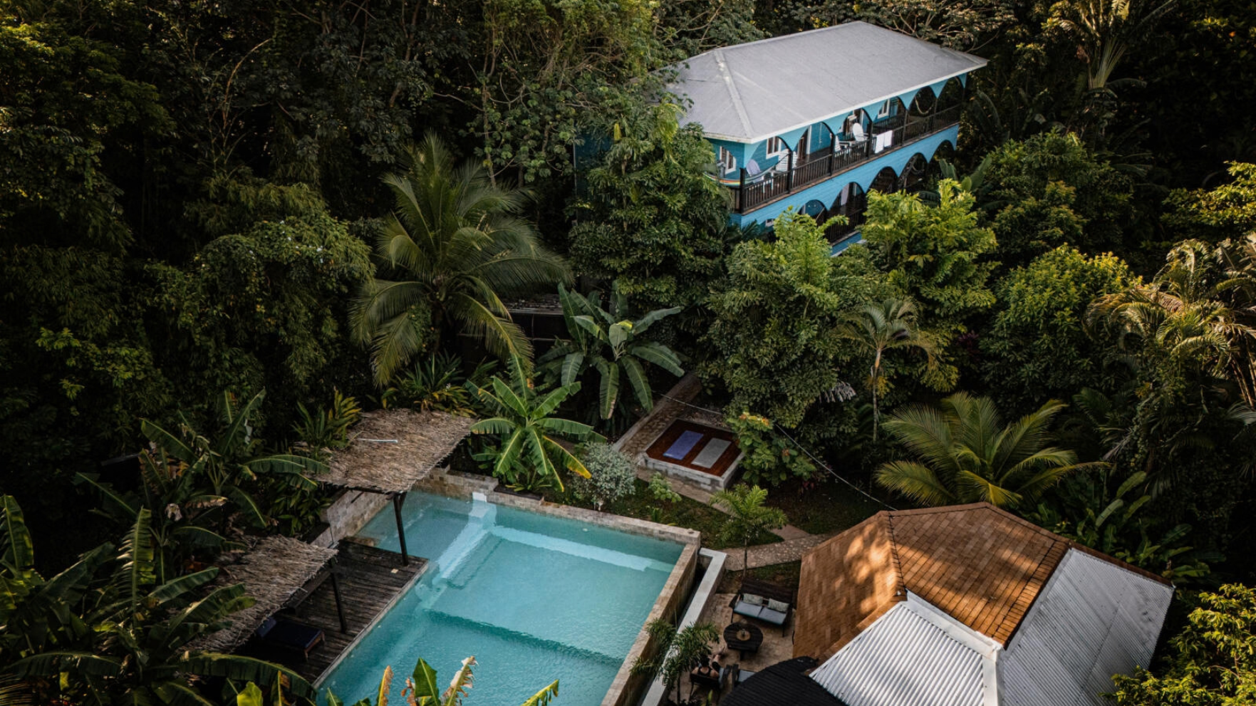 Luchtfoto van Manurii Boutique Hotel met zwembad en blauw gebouw midden in de tropische jungle