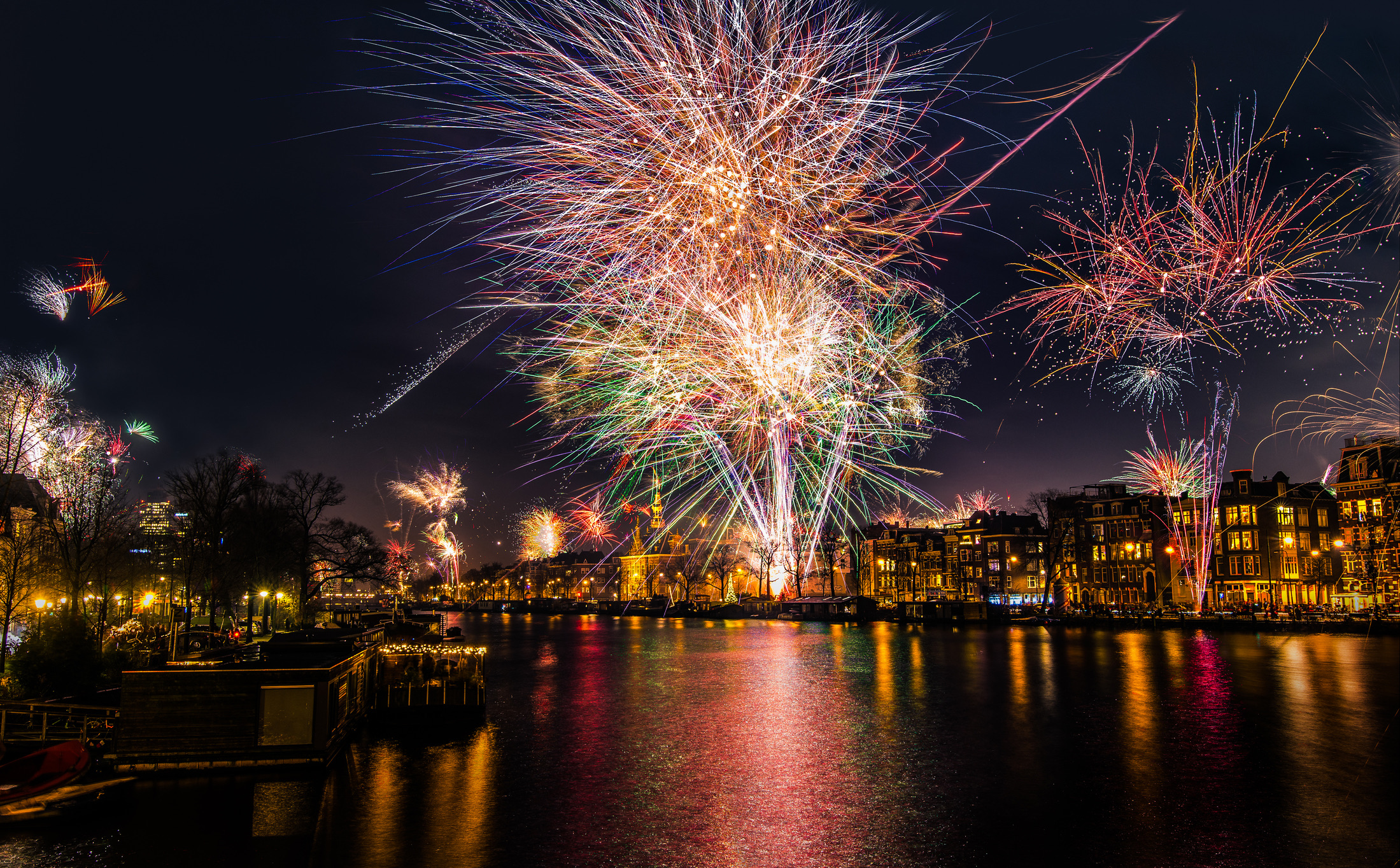 Veel Amsterdammers luiden het nieuwe jaar in met een zak verse oliebollen en appelflappen van de kraam, terwijl het aftellen plaatsvindt op pleinen zoals het Museumplein.