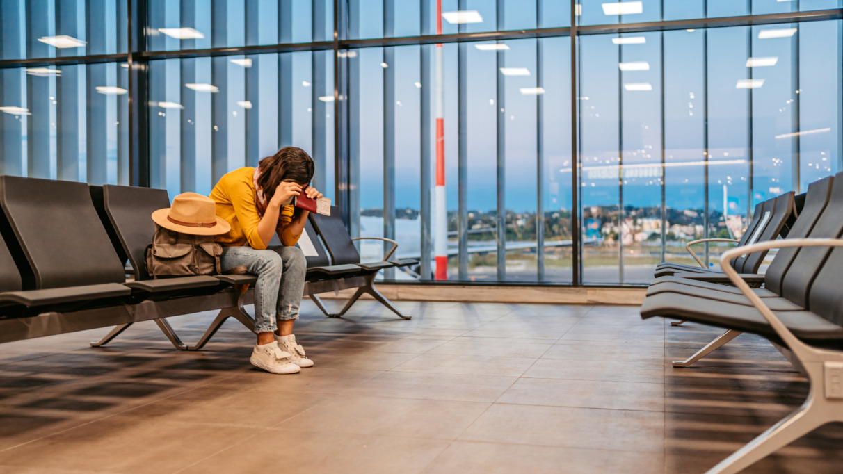 Een vermoeide vrouw die op de luchthaven wacht op haar vertraagde vlucht