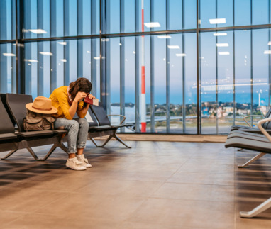 Een vermoeide vrouw die op de luchthaven wacht op haar vertraagde vlucht