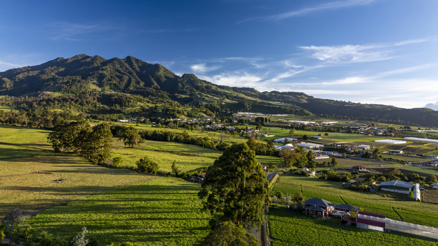 Het dorp Volcán, dat uitkijkt over het omliggende agrarische landschap met vruchtbare groene velden onder een stralend blauwe hemel, Chiriquí, Panama