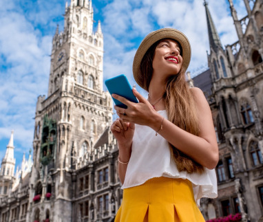 Een jonge toeriste die haar mobiele telefoon gebruikt op het centrale plein voor het beroemde stadhuis in München