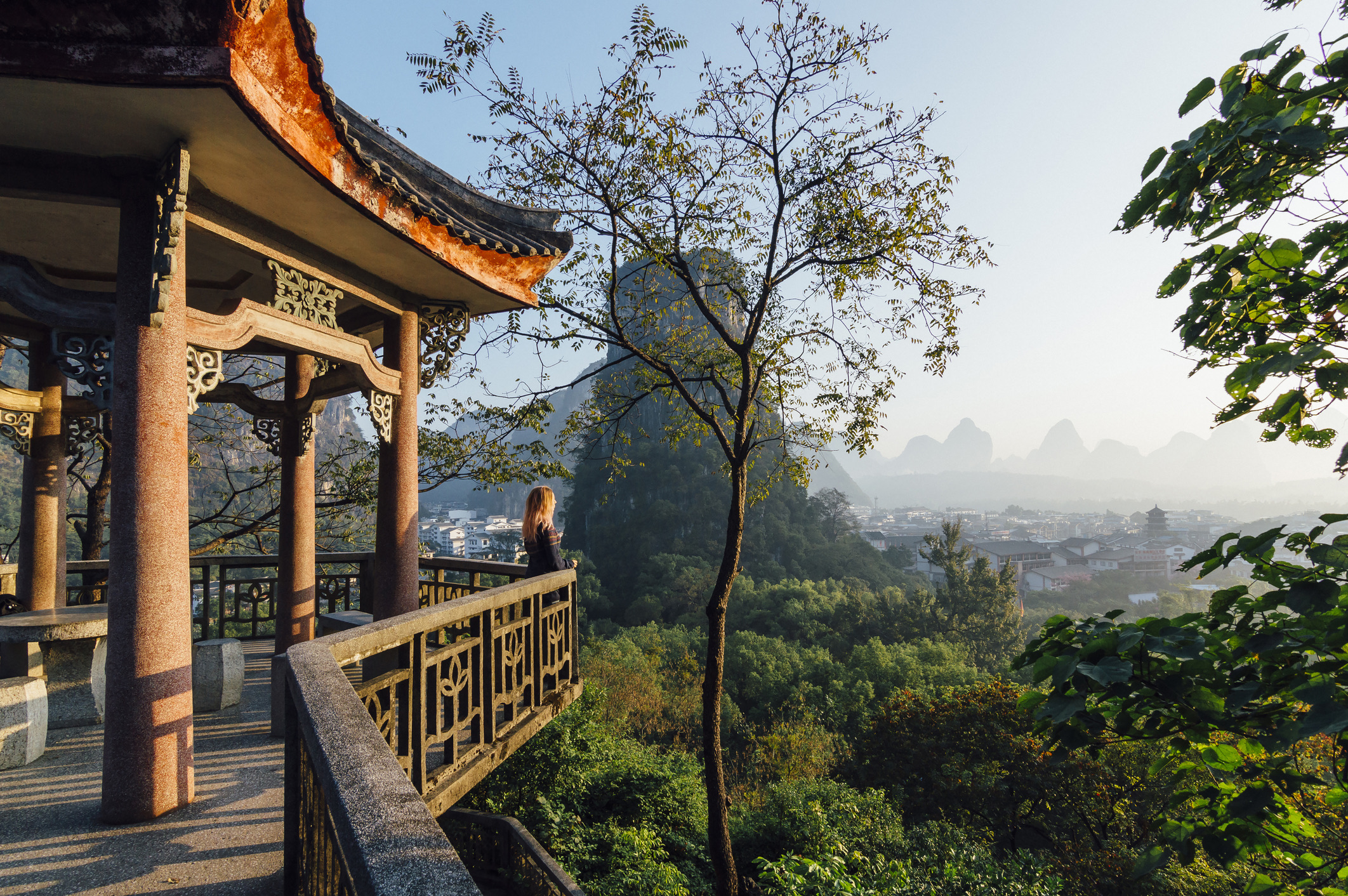 Jonge vrouw geniet van het uitzicht over Yangshuo en de karstbergen in China