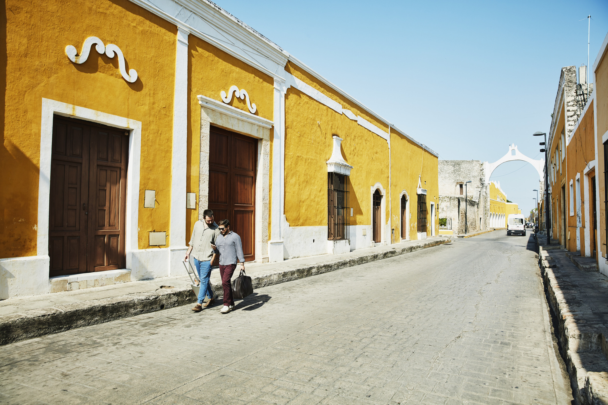 Een homokoppel dat tijdens hun vakantie in het kleine stadje Izamal in Mexico op straat loopt en naar hun smartphone kijkt