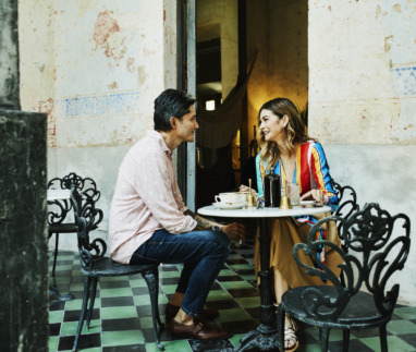 Een glimlachend stel zit op een terrasje en geniet van een kopje koffie tijdens hun vakantie in Izamal, Mexico