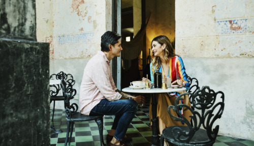 Een glimlachend stel zit op een terrasje en geniet van een kopje koffie tijdens hun vakantie in Izamal, Mexico