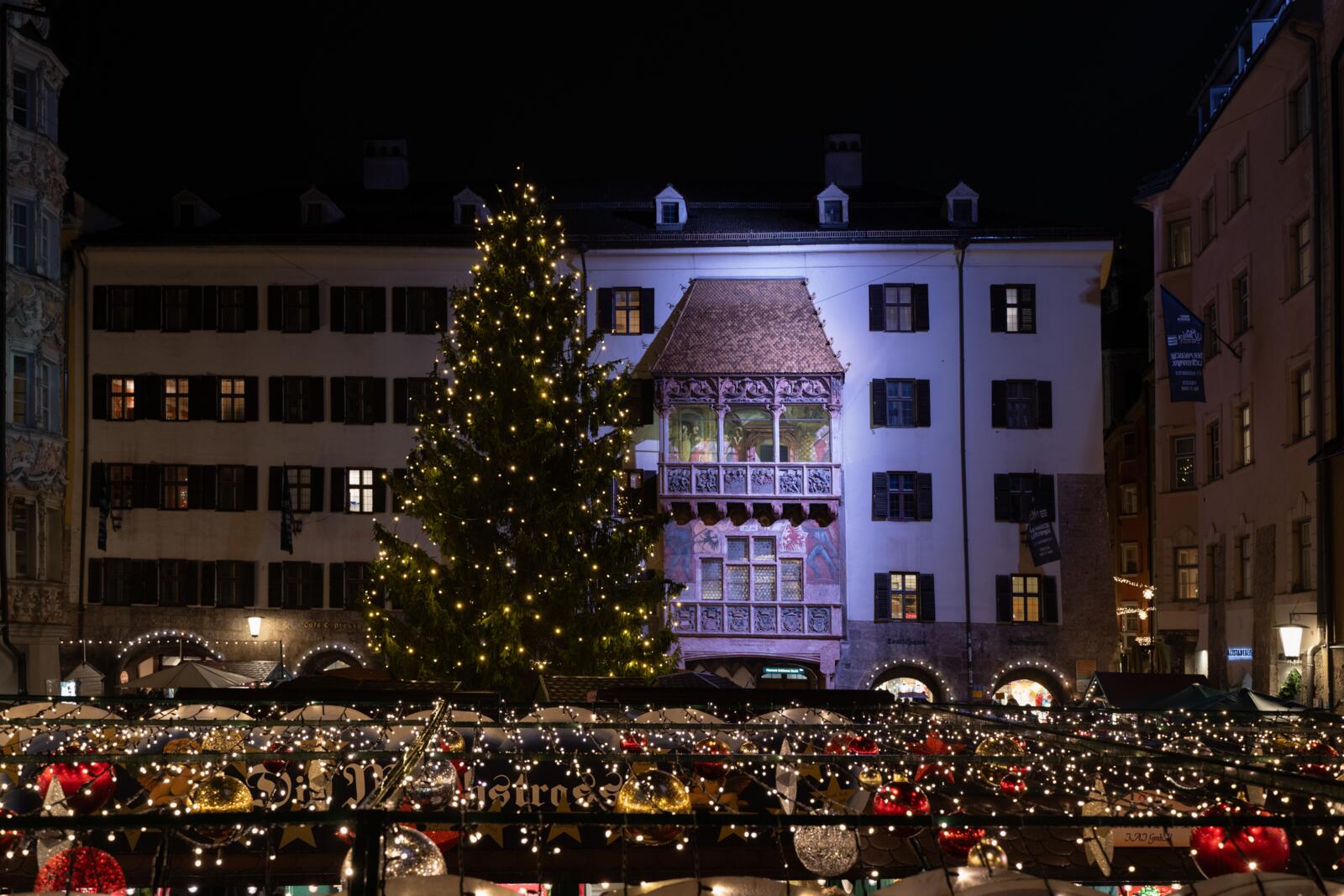 Sfeervol verlichte kerstmarkt voor het Gouden Dak met grote kerstboom in Innsbruck