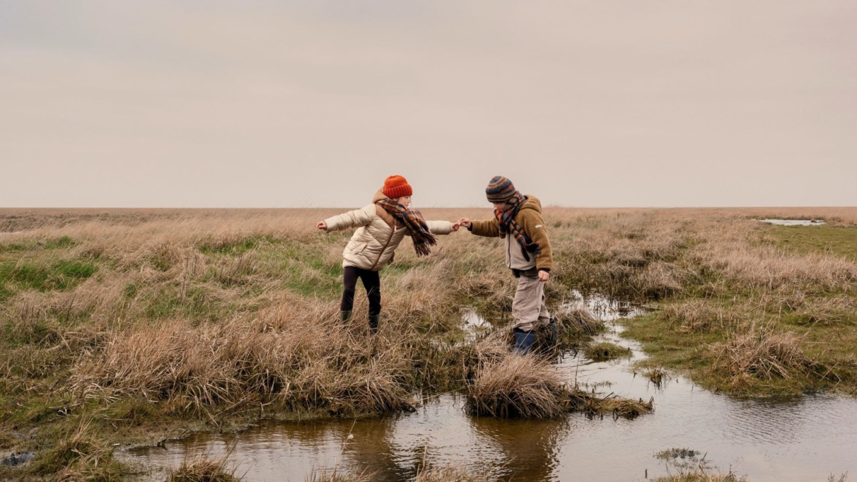 Twee kinderen spelen op natte akkers in het Waddenland