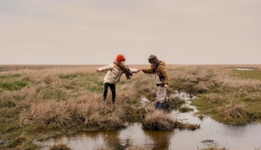 Twee kinderen spelen op natte akkers in het Waddenland
