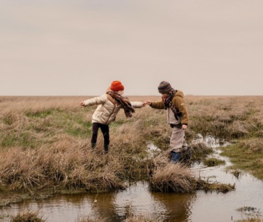 Twee kinderen spelen op natte akkers in het Waddenland