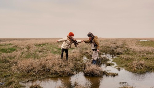 Twee kinderen spelen op natte akkers in het Waddenland