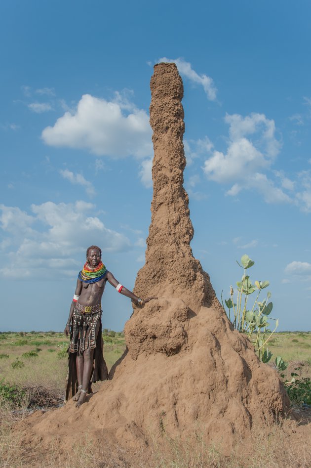De termietenheuvels zijn kenmerkend in het landschap rondom de kraal van deze vrouw van de Nyagatom stam in de omgeving van de Omo rivier in het Zuiden van Ethiopie.