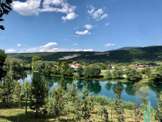 De glasheldere Una doorsnijdt het groene Bosnische platteland