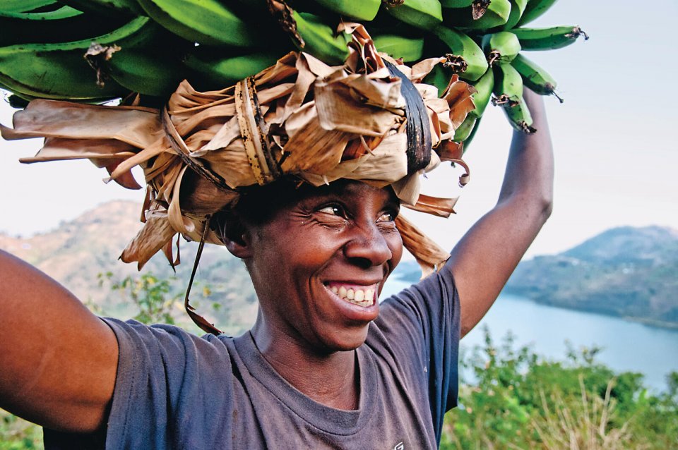 Een vrouw vervoert bananen langs de Congo-Nile Trail. Deze ruim 200 kilometer lange onverharde weg slingert heuvel op en heuvel af langs de oostkant van het Kivumeer. Foto: Tom van der Leij