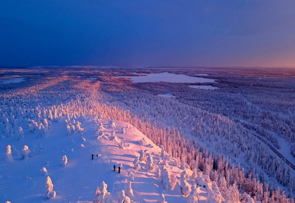 Drie reizigers trotseren de kou (20 graden onder nul) om de adembenemende zonsondergang in de buurt van het wintersportplaatsje Ruka in Fins Lapland te zien. Foto: Morris Bennis