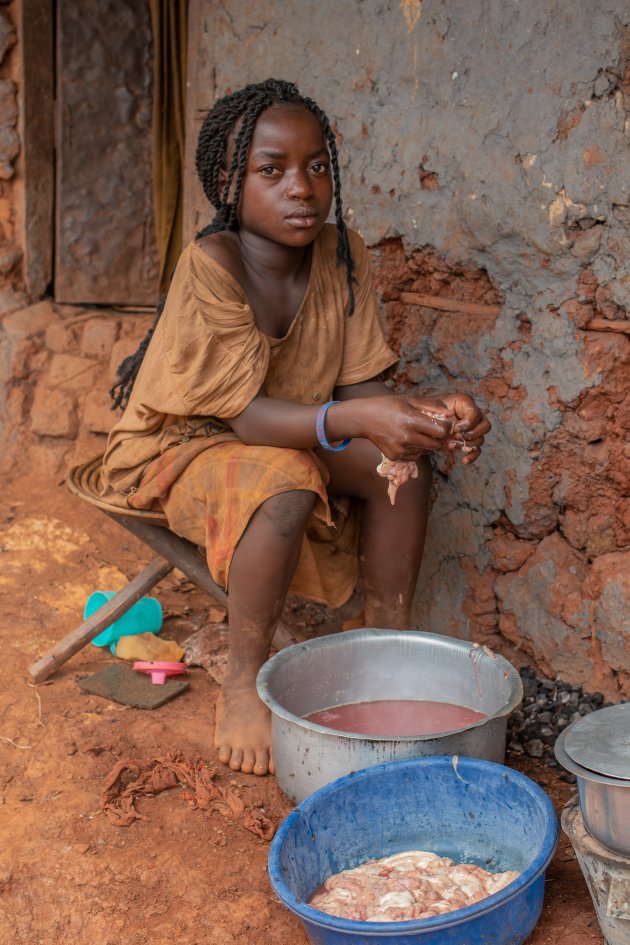 Oegandese meisje voorbereid vlees in een kom