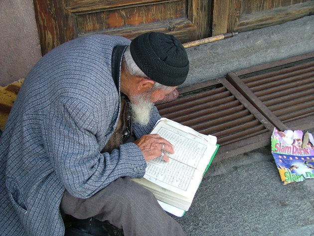 Oude man verdiept in de koran