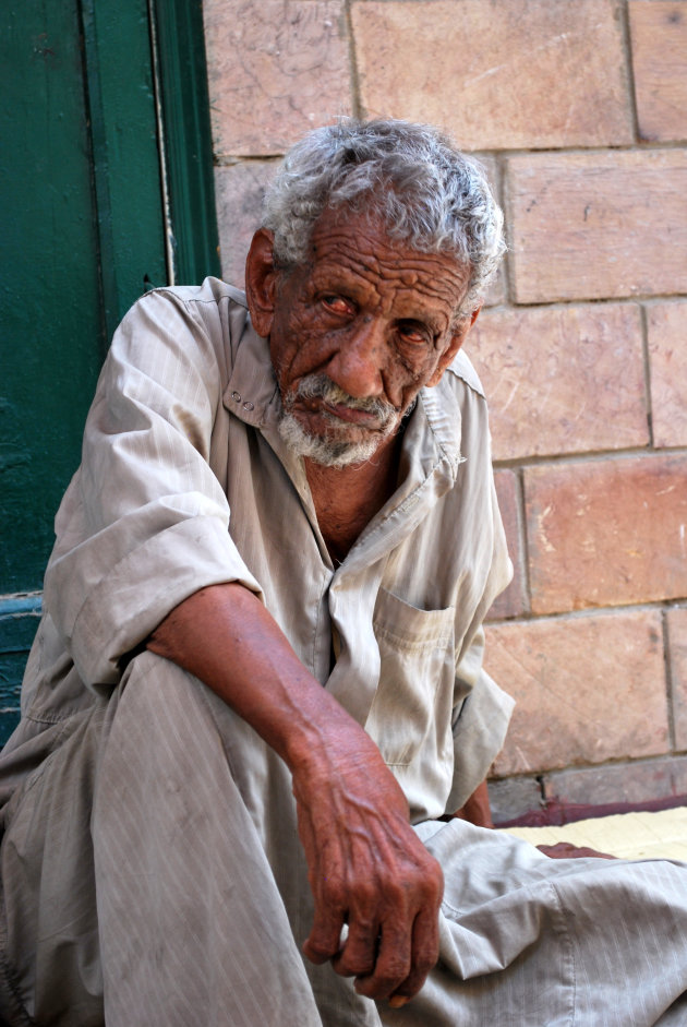 Oude man op de stoep van souq in Aswan