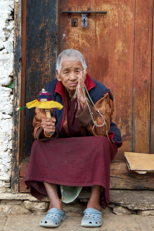 Mediterende Bhutanese dame bij de oudste tempel van Bhutan