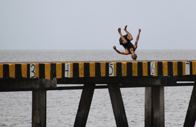 Een jongen maakt een salto van een pier in Granada