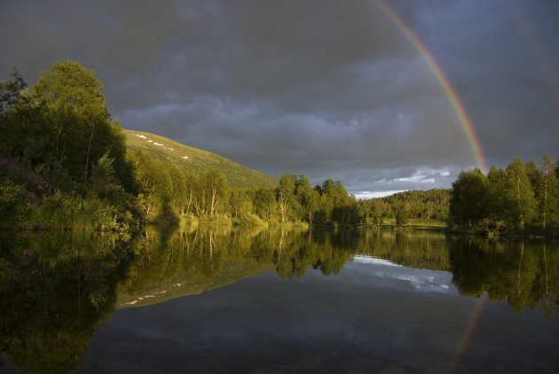 Reflectie regenboog en bergen bij de poolcirkel