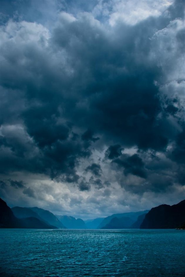 Fjord met donkere wolken en schittering op het water