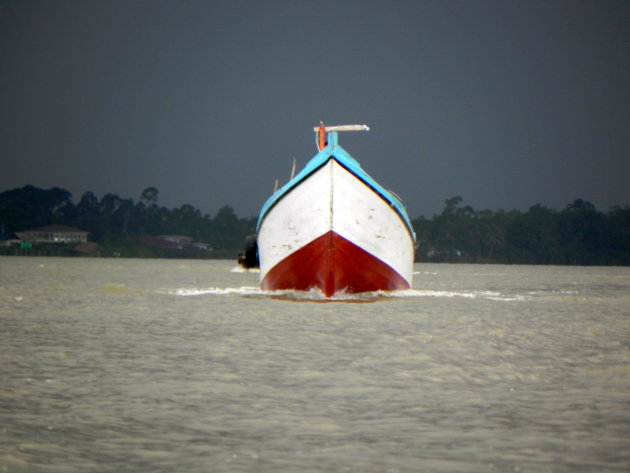Houten boot in slecht weer op de Surinamerivier.