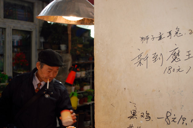 man koopt sprinkhaan op markt in Shanghai