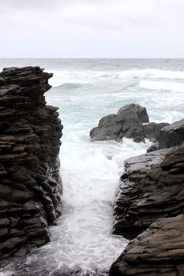 Kolkende golven tussen de rotsblokken van lava