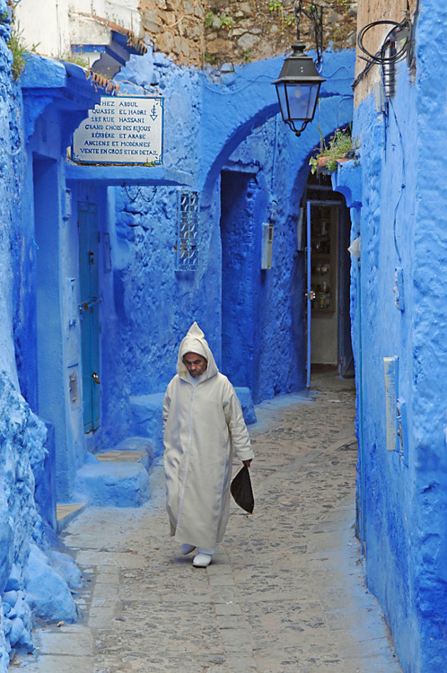 Traditioneel geklede man in blauw straatje te Chefchaouen