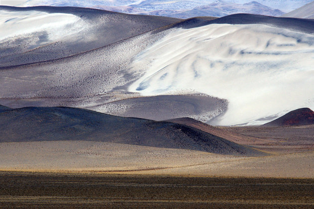 Wit zand over zwarte lavaheuvels in de Andes