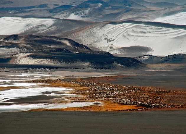 Lavastof, zand en grassen in vulkanisch landschap.